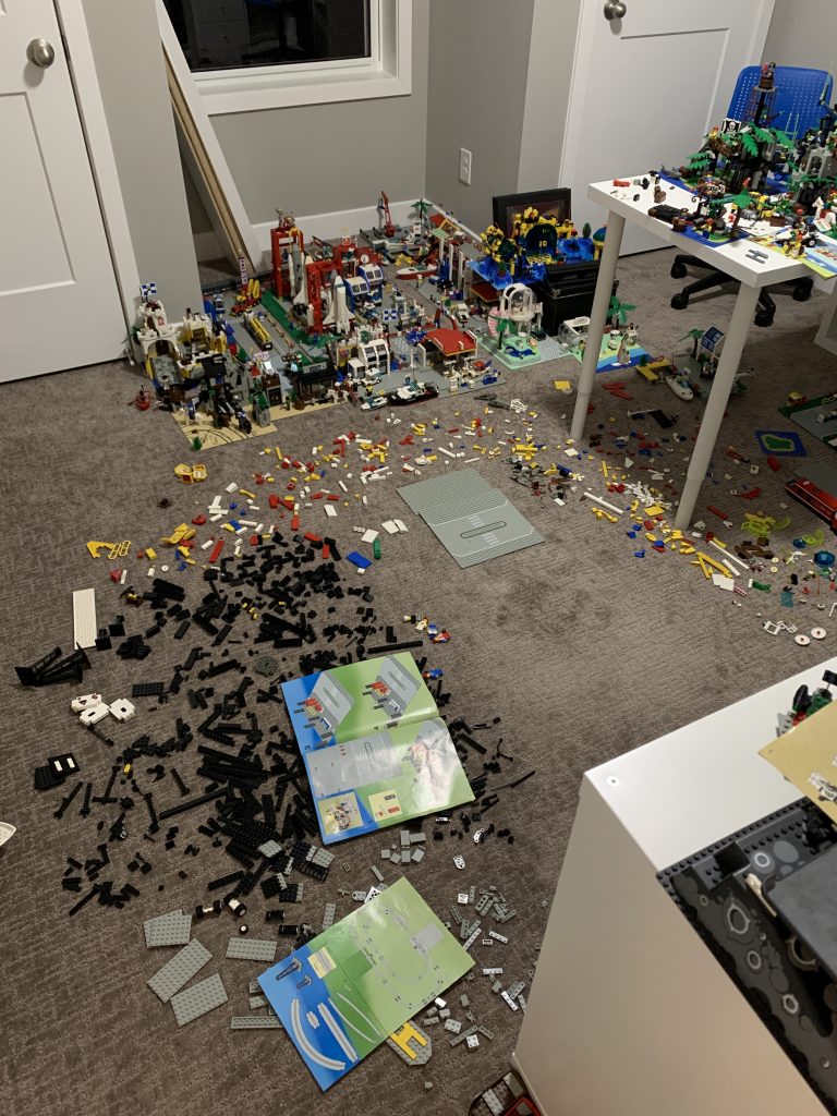 Photograph of very little LEGO brick left on the floor. Many sets put together in the background.