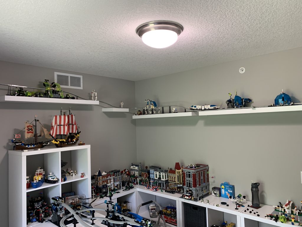 Photograph of game room, shelving along wall now expands secondary wall with tram riding up along that wall.