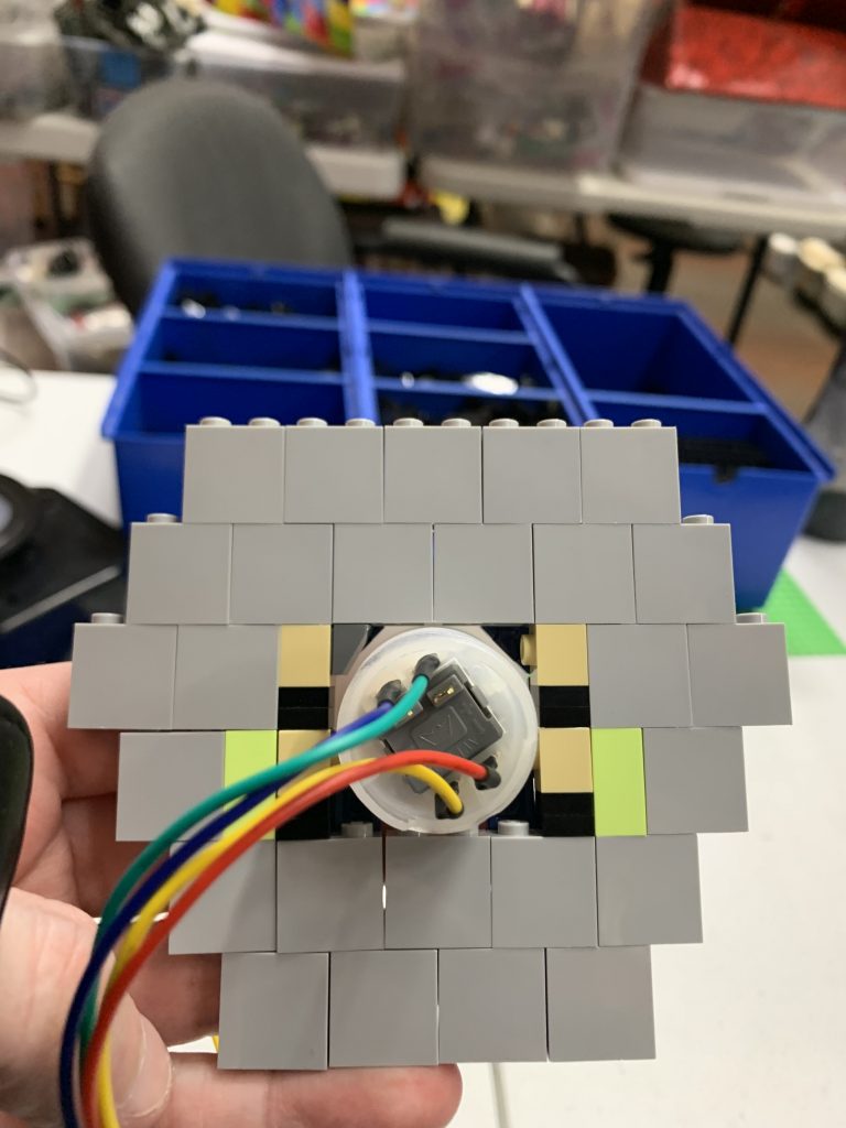 Photo showing the button being cradled from the back of the bricks.