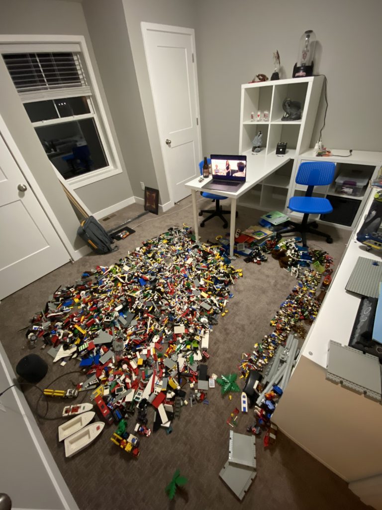 Photograph of LEGO brick all over the floor mixed together in room with empty shelves and tables.