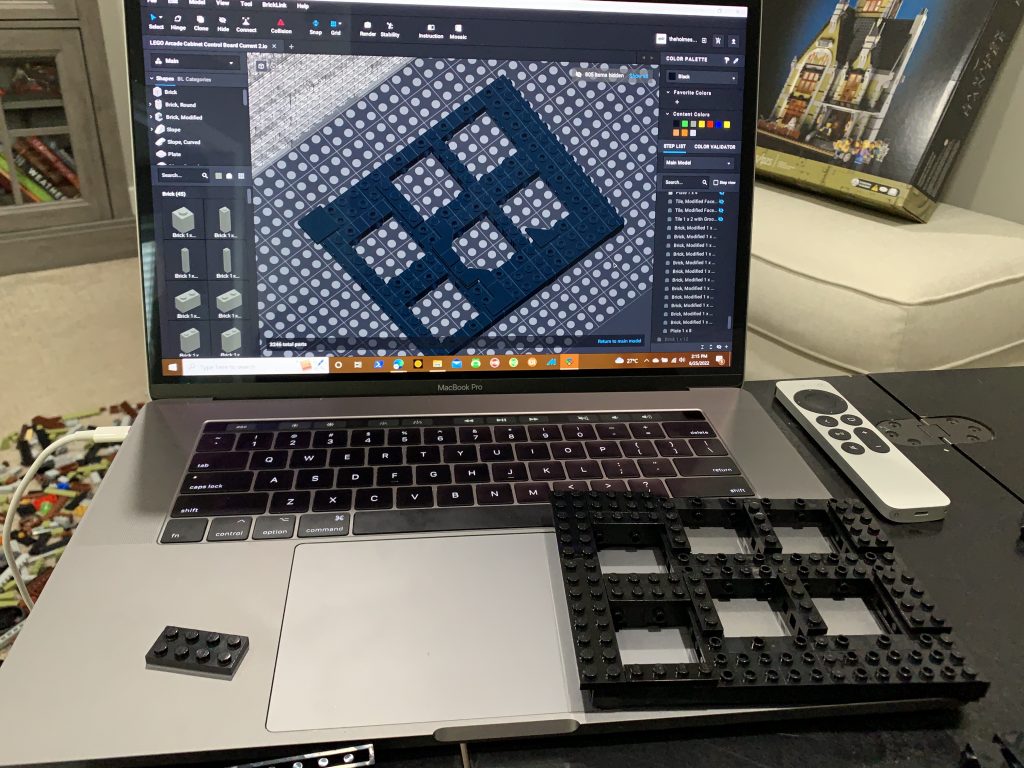 Photo of computer running software showing design of the button panel with the physically built button panel resting on the top of the computer.