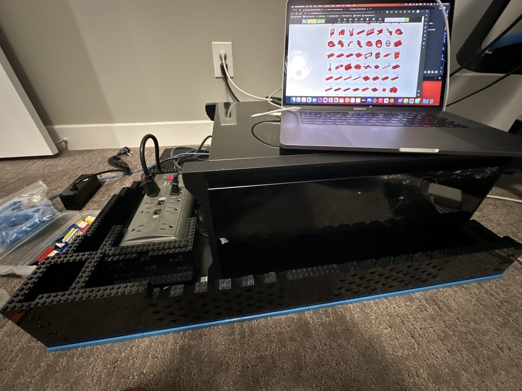 Photo of base being built up. Ventilation system started with PC sitting inside the base and design laptop on top of that showing Bricklink page of red parts.