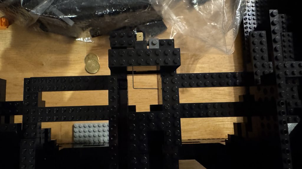 Top-down photo showing the lever attached to the switch sitting in the middle of the opening at the end of the coin chute